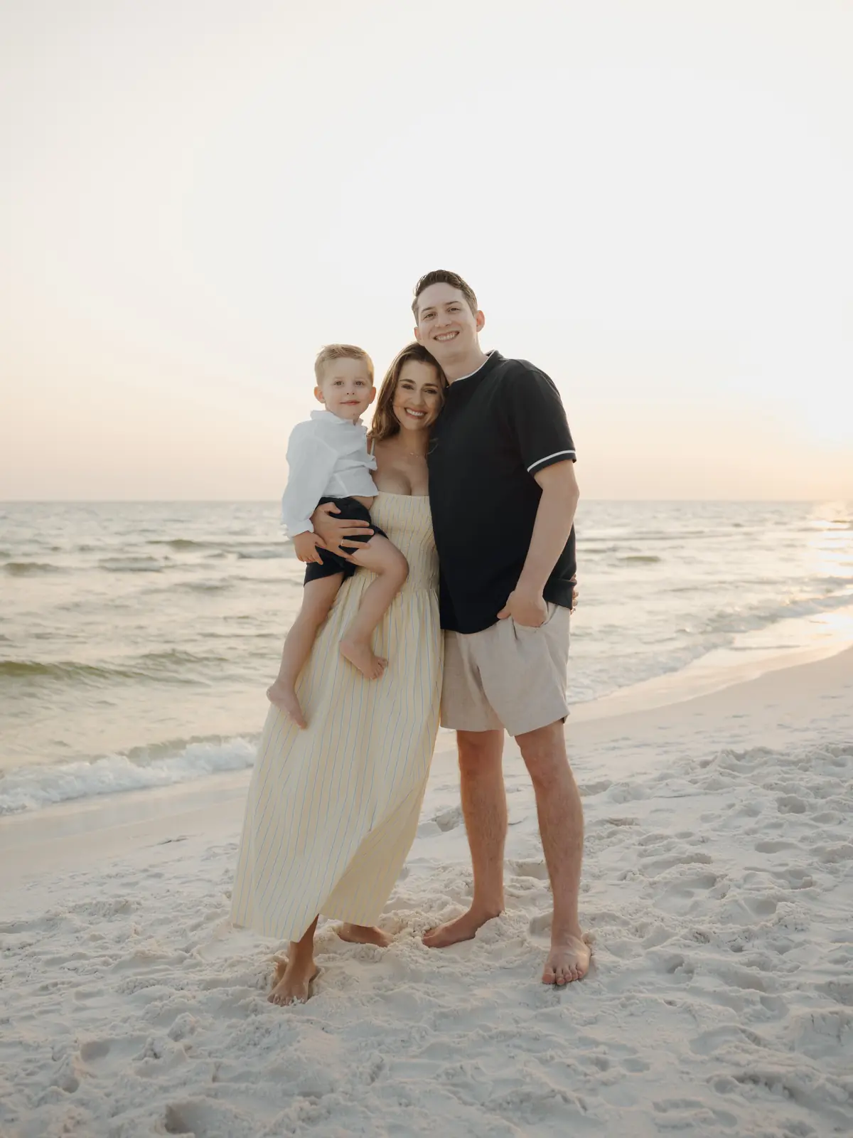 Parents and son on the shoreline at sunset