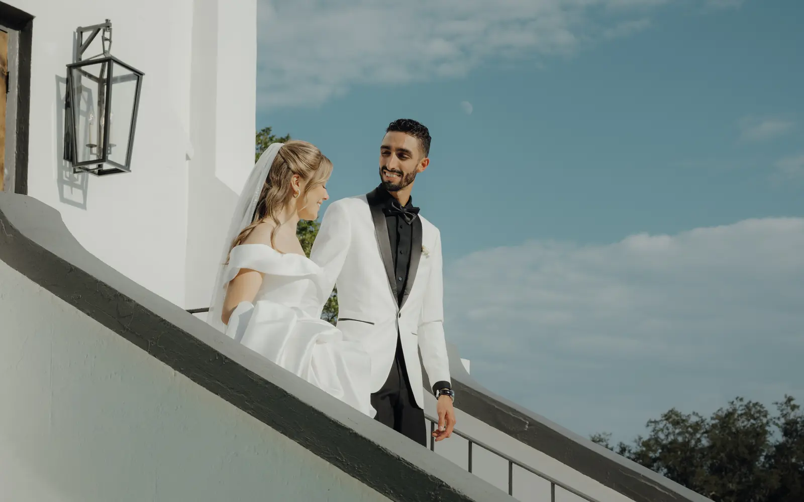 Bride and groom on white steps beside a lantern