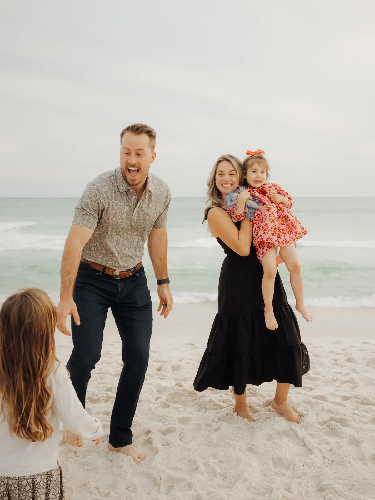 Family laughing and walking on the sand