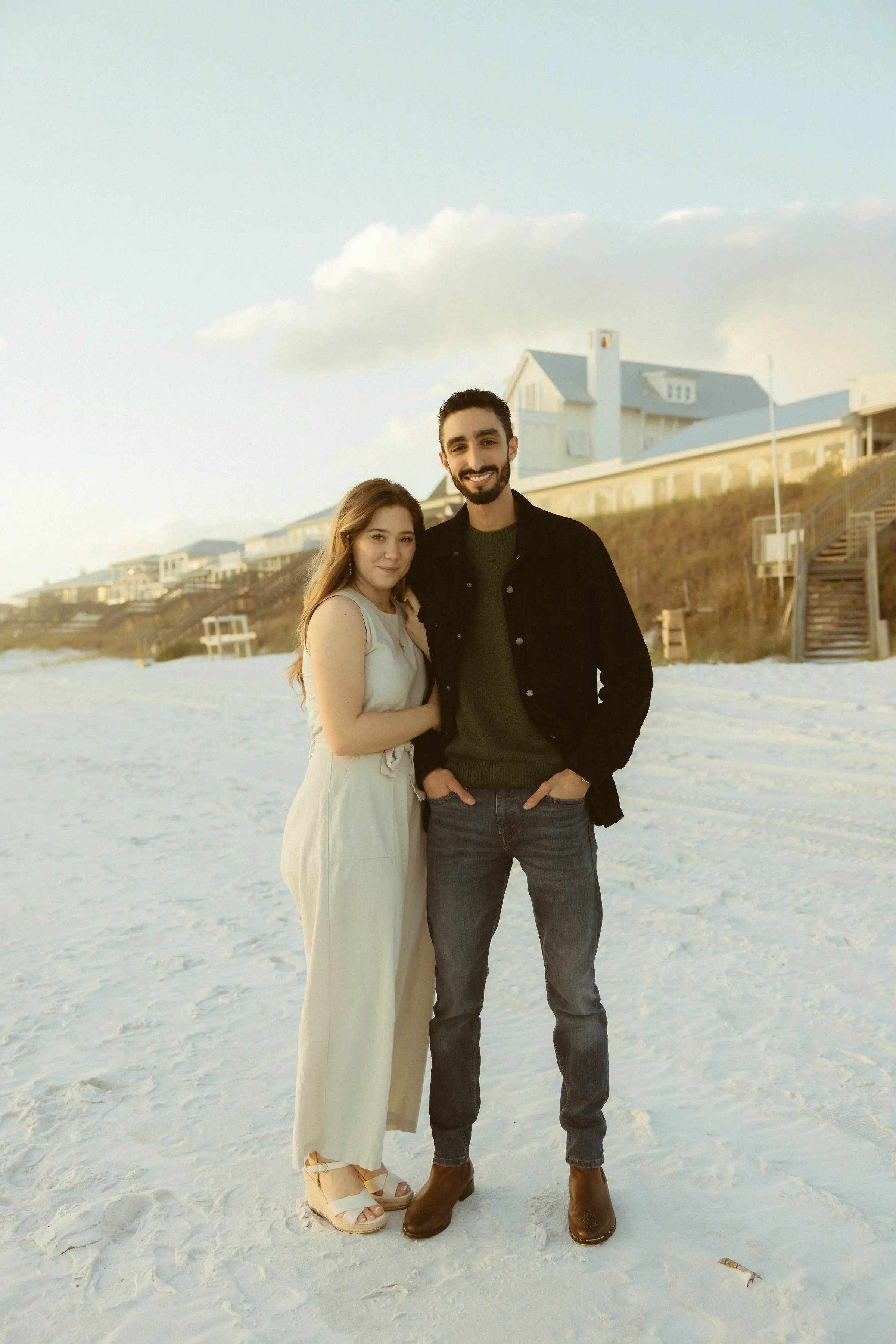 Couple on white sand in front of a dune house