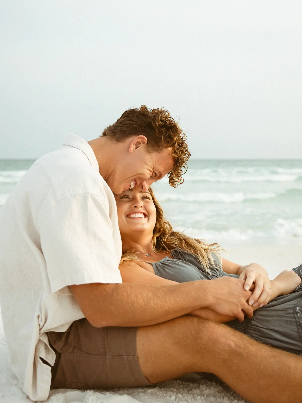 Couple sitting together on the sand by the waves