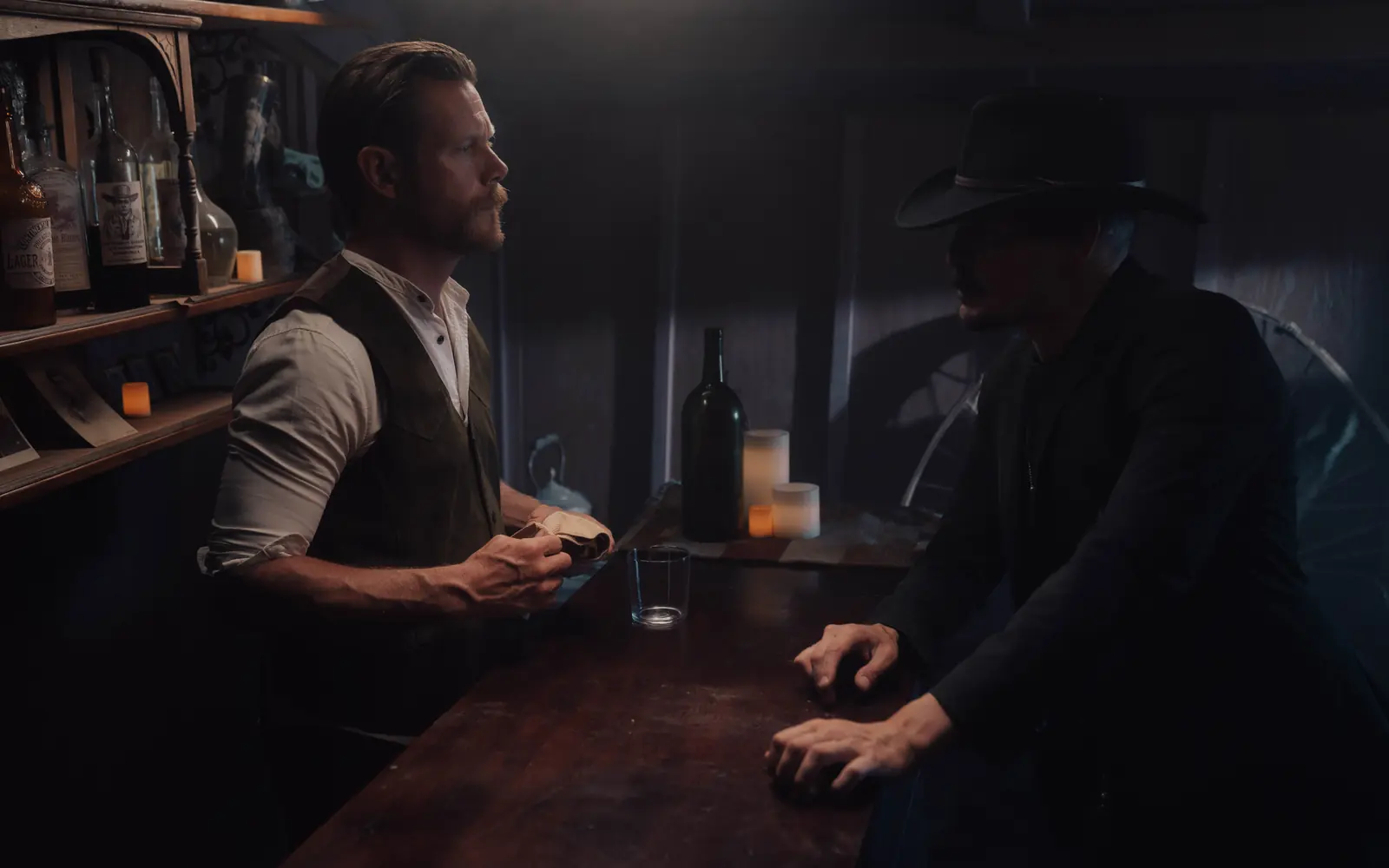 Two men talking in a dark, moody bar