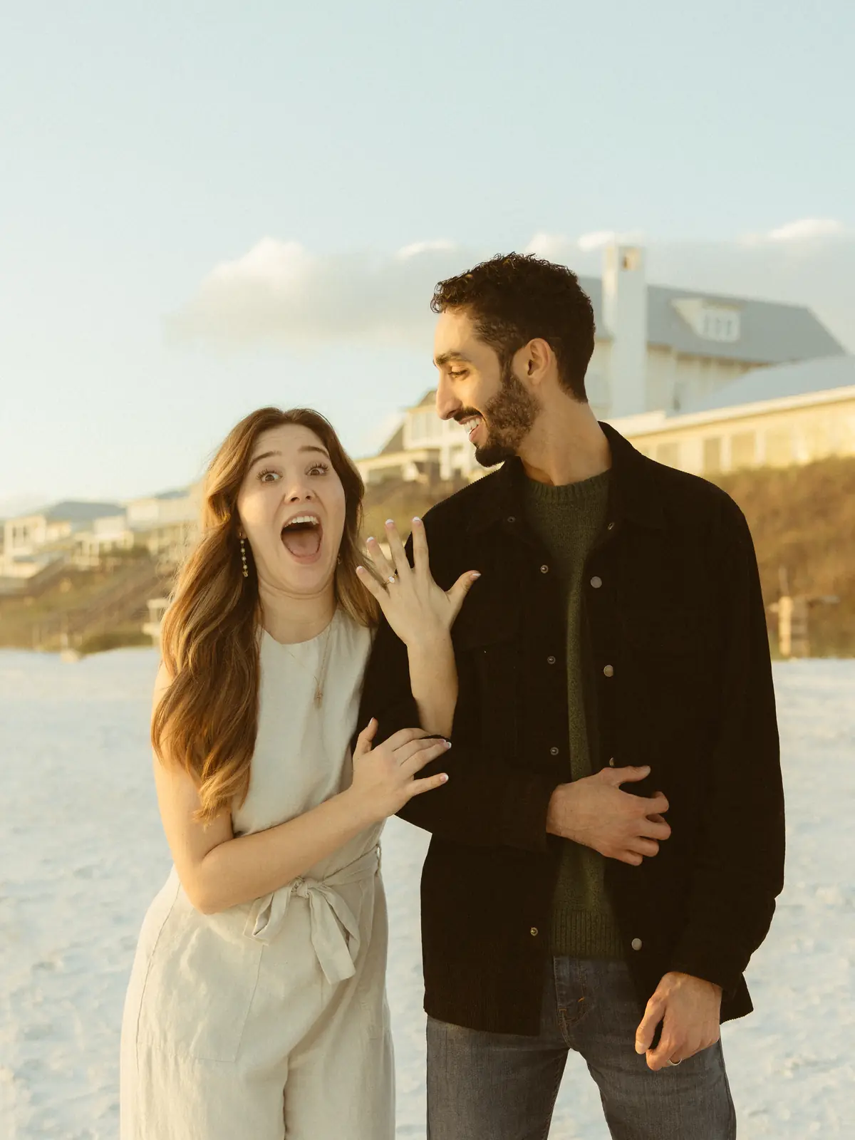 Excited couple showing an engagement ring on the beach