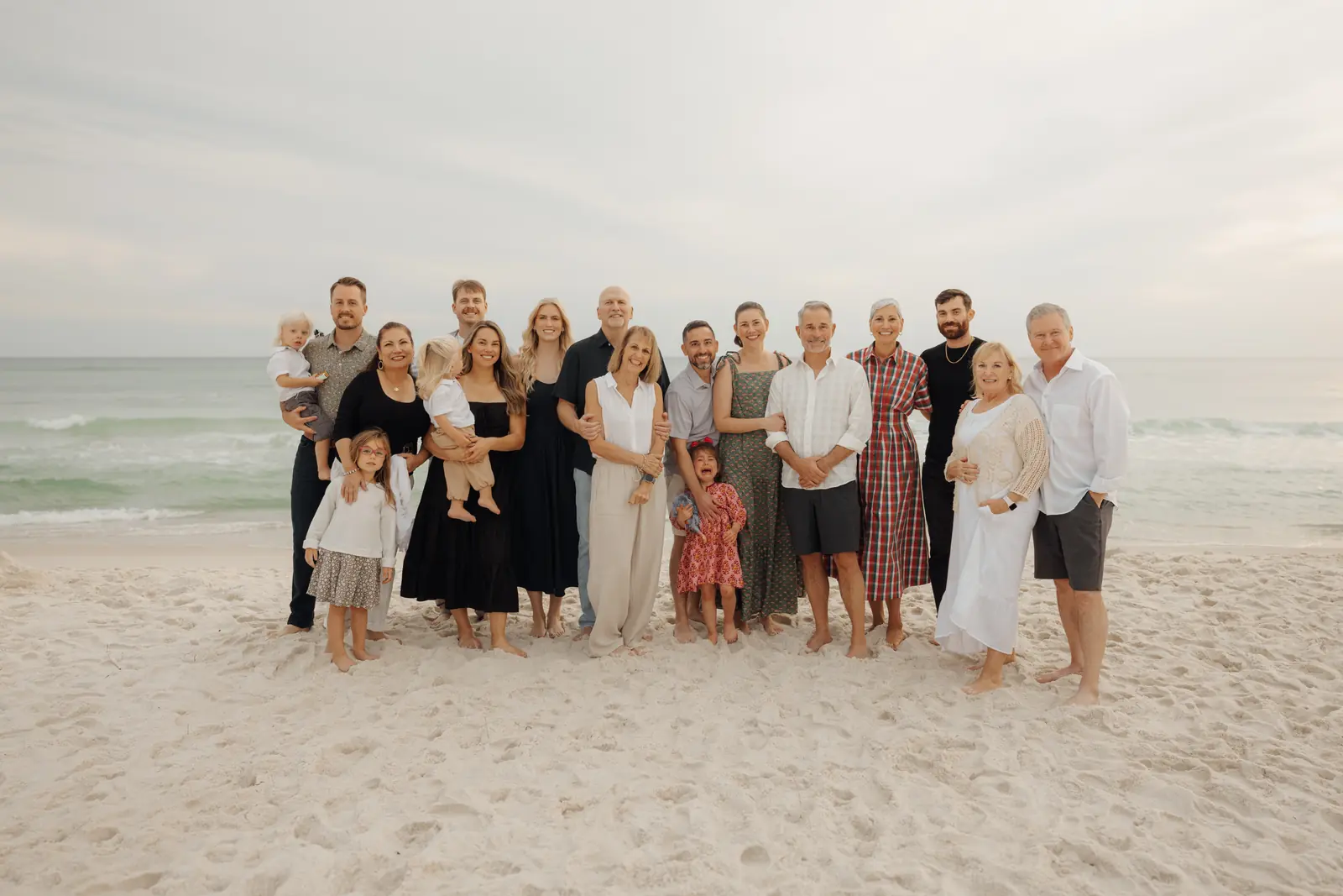 Large extended family group photo on a white sand beach