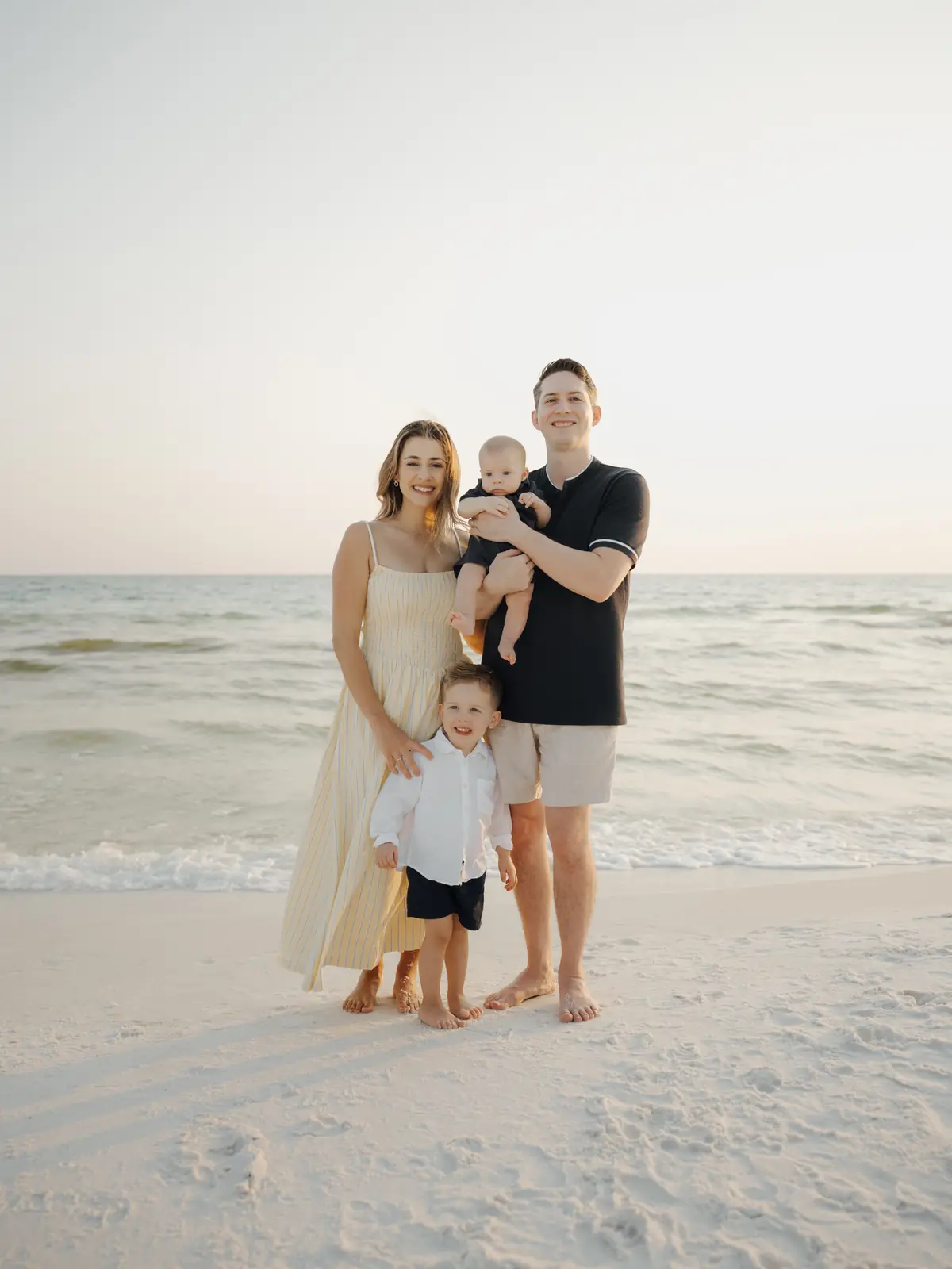 Parents with two young boys on the beach at sunset