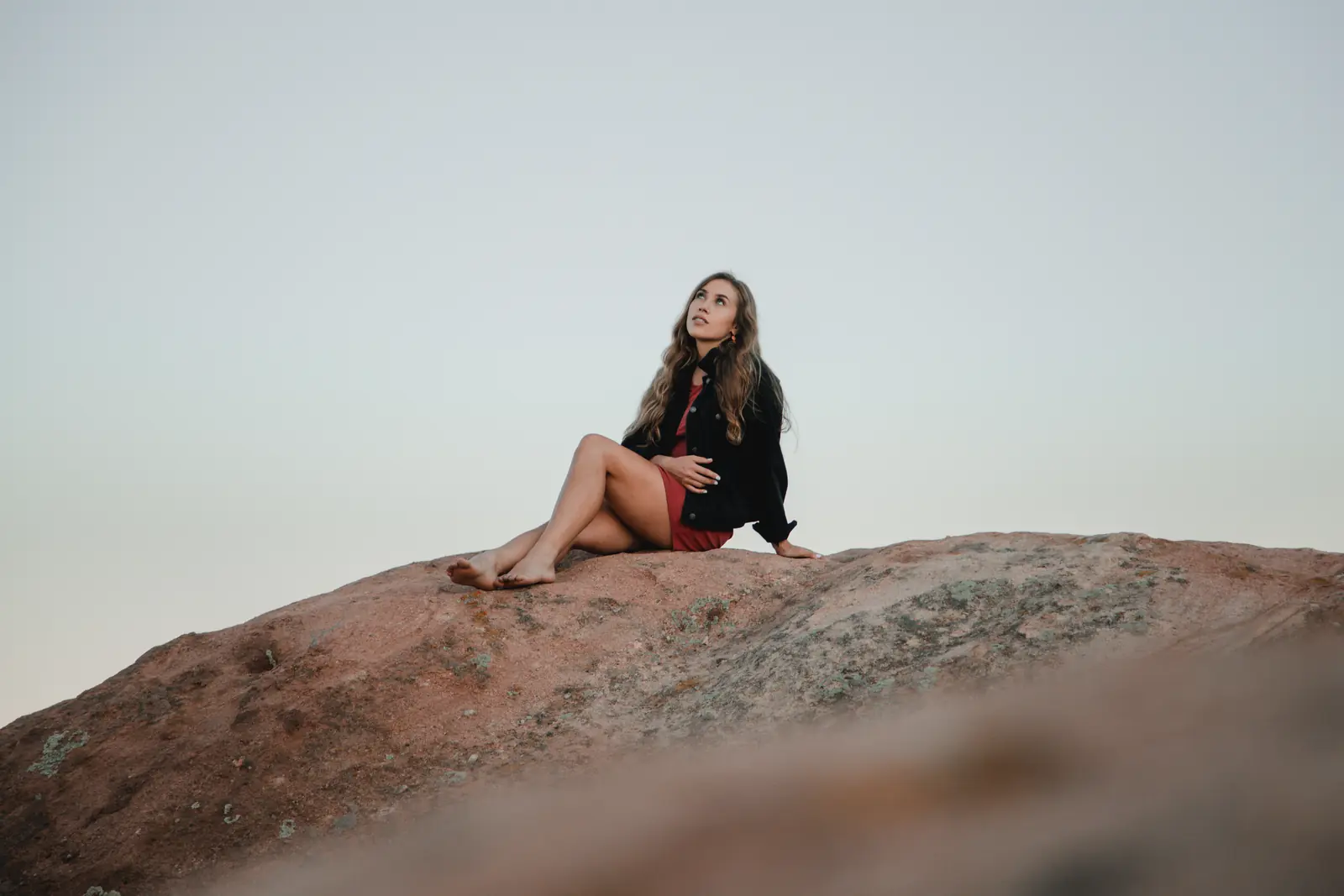 Woman seated on red rocks at dusk