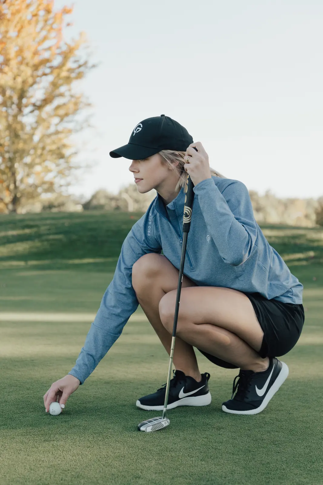 Golfer in branded apparel placing a ball on the green