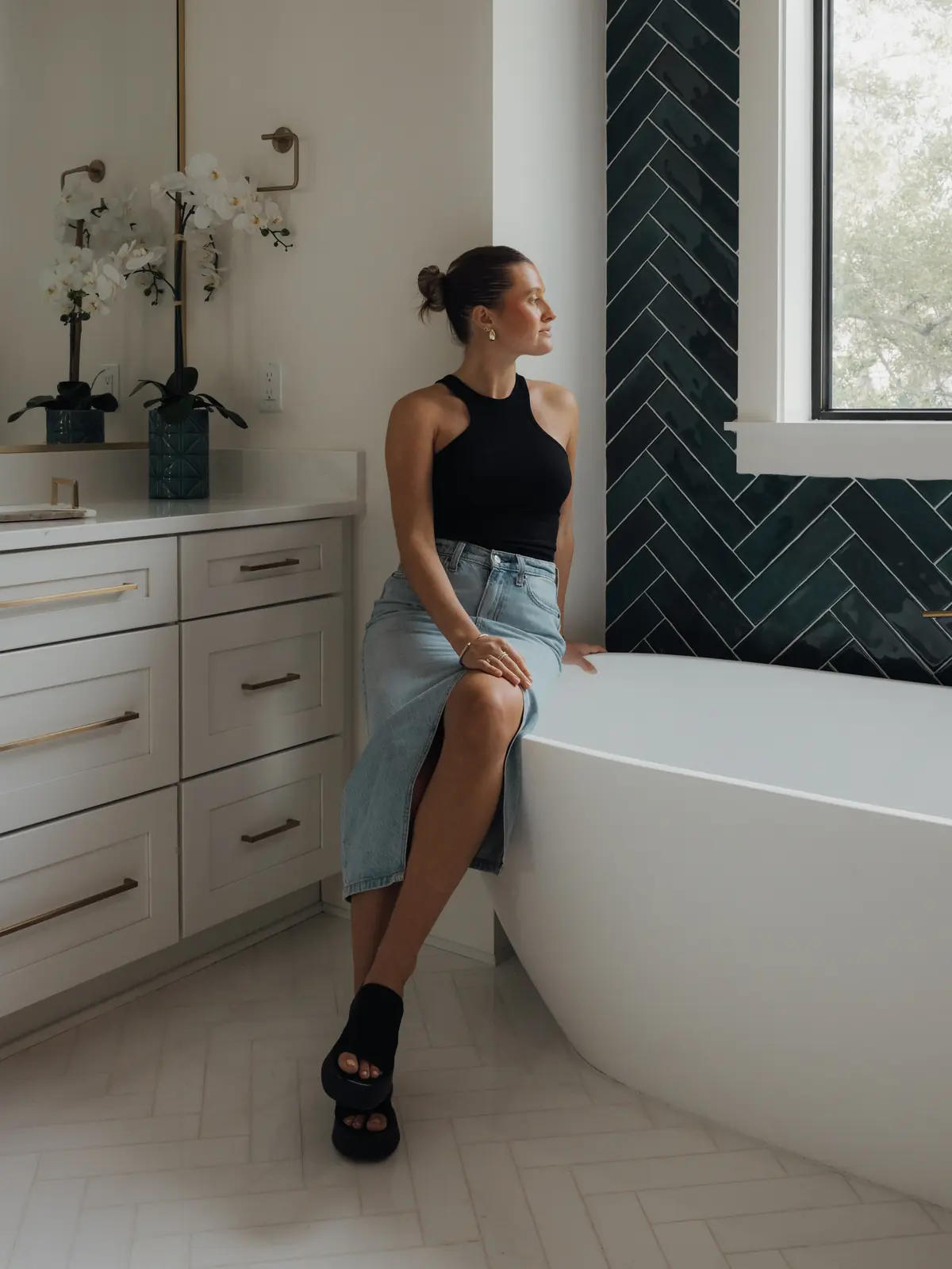 Woman sitting on the edge of a tub in a bright bathroom
