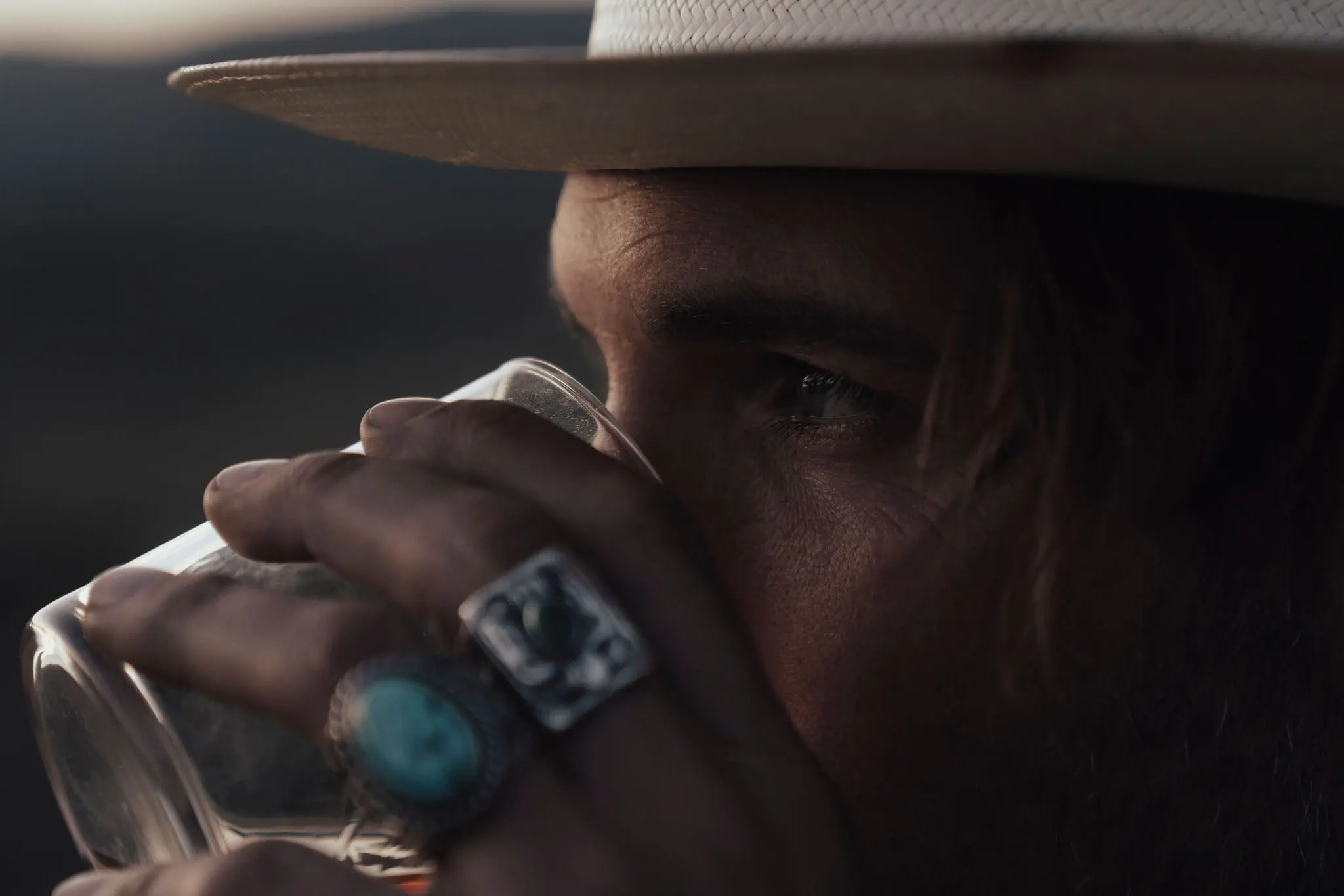Moody close-up of a man in a hat with turquoise rings
