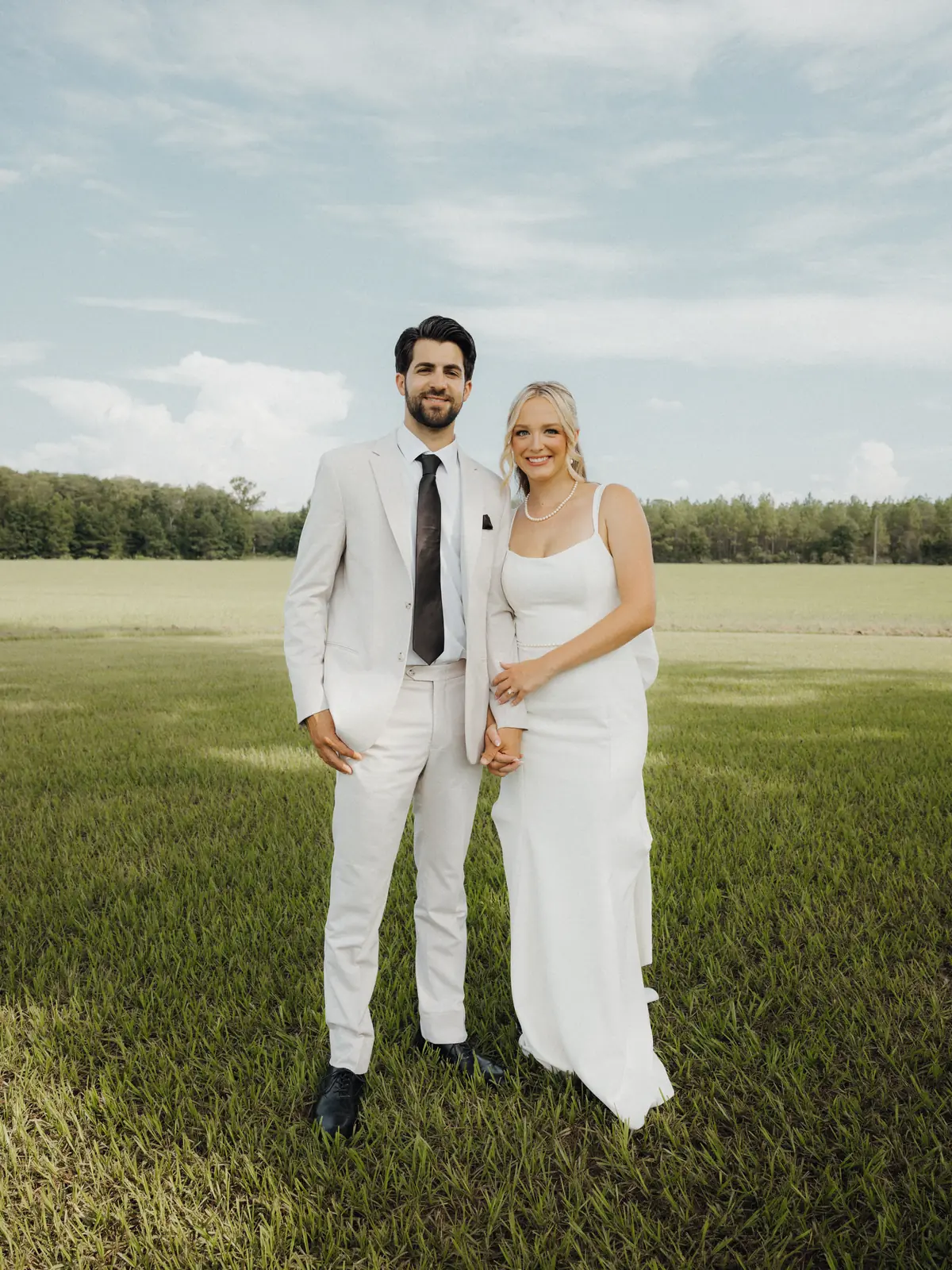 Bride and groom standing in an open green field