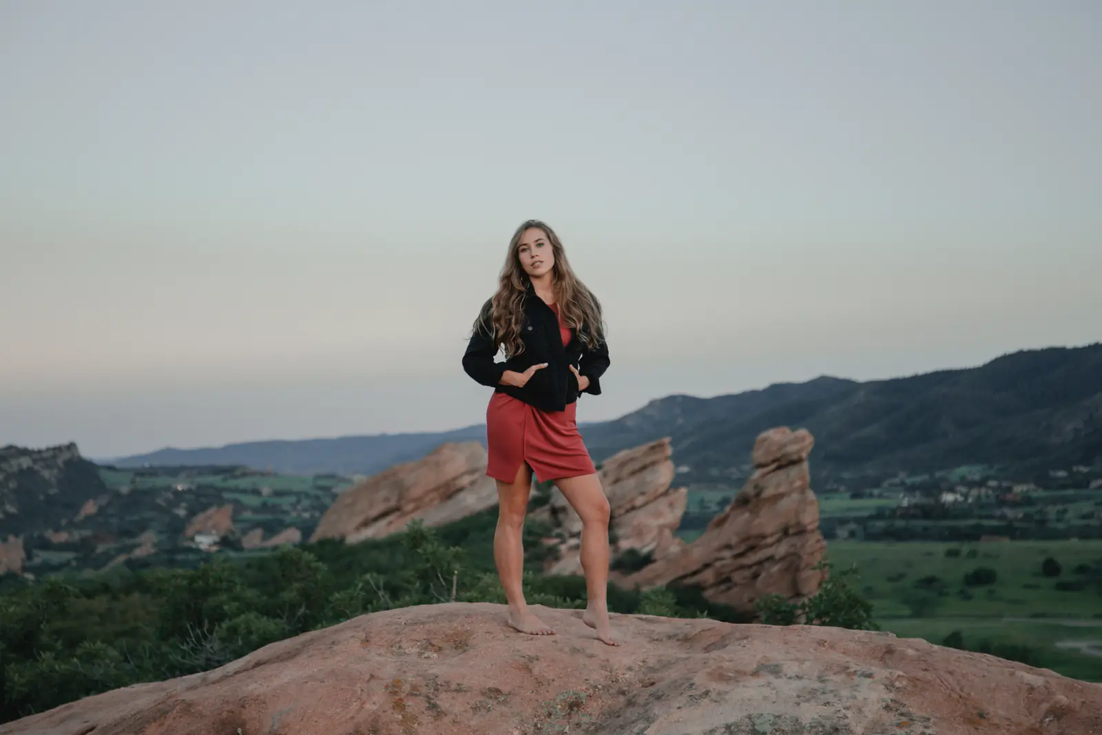 Woman in a red skirt standing on rocks at dusk