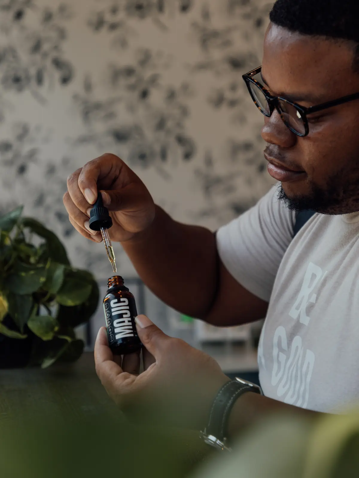 Man using a dropper bottle in a styled interior